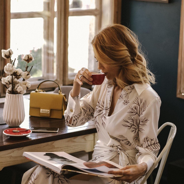 Perimenopauza, žena sedi, pije kafu i uživa dok čita